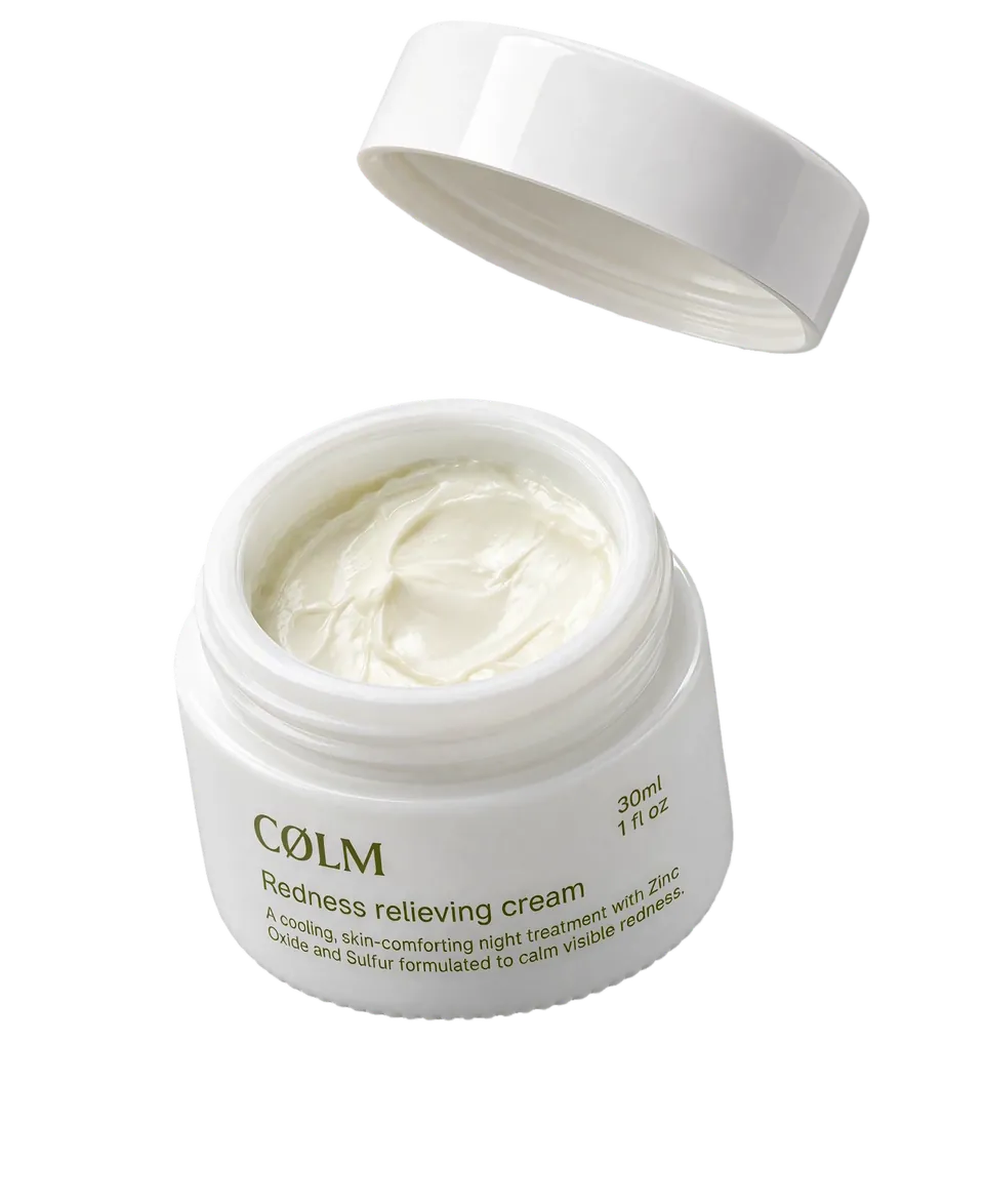CØLM Redness Relieving Cream med låget svævende over den åbne krukke, så den lyse creme ses